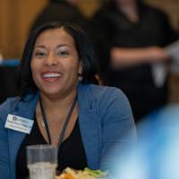 An alumni staff member smiles at a table